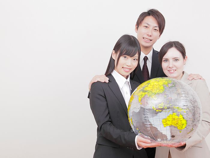 地球儀を持つ外国人女性と日本人の男女